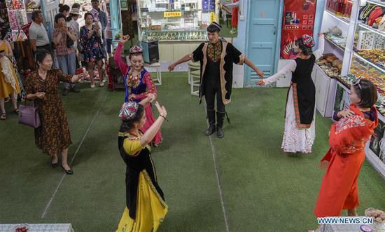 Tourists watch a performance staged by locals in the ancient city of Kashgar, northwest China's Xinjiang Uygur Autonomous Region, July 9, 2019. In the first half of 2019, the ancient city of Kashgar received over 310,000 tourists. (Xinhua/Zhao Ge)