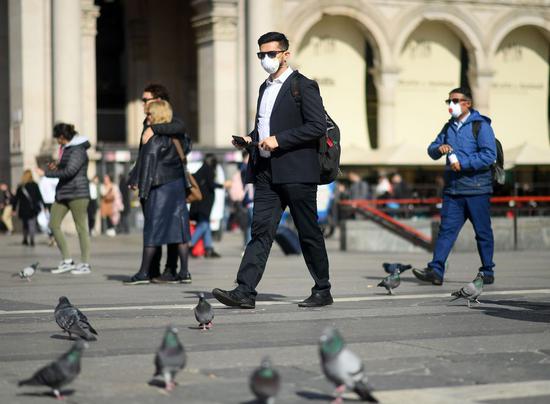 People wear masks as they walk in Milan, Italy, on Feb. 24, 2020. (Photo by Daniele Mascolo/Xinhua)